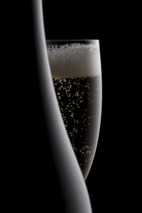 Ausschnitt einer Sektflasche und eines Sektglases vor schwarz Ausschnitt einer Sektflasche und eines Sektglases vor schwarz