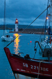In the evening at the lighthouse of Eruqy - harbor entrance with boats. Brittany, France In the evening at the lighthouse of Eruqy - harbor entrance with boats. Brittany, France