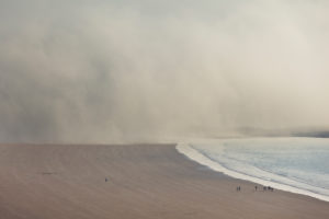 Tidal fog moves over the beach at Eruy. A small group of people (right) shows the proportions. Erquy, Brittany, France Tidal fog moves over the beach at Eruy. A small group of people (right) shows the proportions. Erquy, Brittany, France