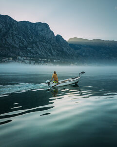 Bay of Kotor in Montenegro on the Adriatic Sea, sunrise, boat on the water in the morning mist