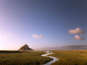 Le Mont-Saint-Michel at sunset. A small stream meanders towards the Klosterberg Le Mont-Saint-Michel at sunset. A small stream meanders towards the Klosterberg