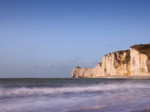 The cliffs of Étretat glow in the evening sun. View from the beach to the Porte D'Amont rock gate The cliffs of Étretat glow in the evening sun. View from the beach to the Porte D'Amont rock gate