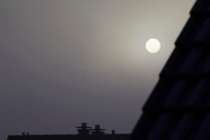 The sun behind thick clouds in the dark gray sky The sun behind thick clouds in the dark gray sky