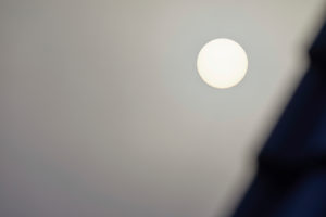 The sun behind thick clouds in the dark gray sky The sun behind thick clouds in the dark gray sky