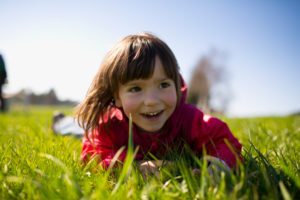 5-year-old girl lying with red jacket on a green meadow 5-year-old girl lying with red jacket on a green meadow