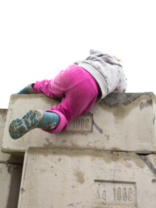 4-6 jähriges Kind mit pinker Hose klettert über Betonsteine 4-6 jähriges Kind mit pinker Hose klettert über Betonsteine