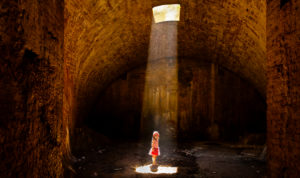 4-6 years old girl in striped dress in the cellar standing in the light cone 4-6 years old girl in striped dress in the cellar standing in the light cone