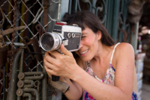 30-40 years old woman in dress at metal grid with Super8 camera in the hand 30-40 years old woman in dress at metal grid with Super8 camera in the hand