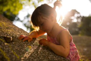 4-6 jähriges Mädchen malt mit Kreide auf graue Mauer, Sonne, Gegenlicht 4-6 jähriges Mädchen malt mit Kreide auf graue Mauer, Sonne, Gegenlicht