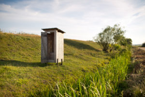 Wooden outhouse on the edge of a street on a meadow Wooden outhouse on the edge of a street on a meadow