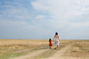 30-40 years old mother with 4-6 years old child walking hand in hand on a country lane 30-40 years old mother with 4-6 years old child walking hand in hand on a country lane