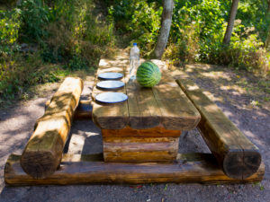 gedeckter Holztisch mit Holzbank mit drei Tellern und einer grünen Melone gedeckter Holztisch mit Holzbank mit drei Tellern und einer grünen Melone