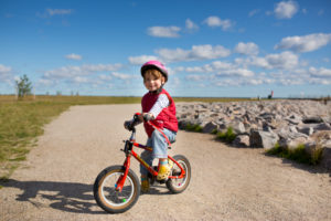 4-6 jähriges Mädchen fährt auf rotem Kinderfahrrad auf einen Weg an der Ostseeküste 4-6 jähriges Mädchen fährt auf rotem Kinderfahrrad auf einen Weg an der Ostseeküste