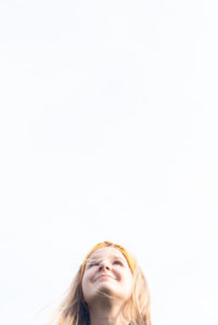 Girl, 8 - 12 years old, looks up smiling, long hair, blond, schoolgirl, white background.