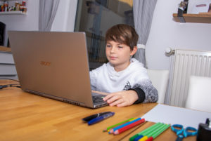 Junge sitzt im Homeschooling vor einem Laptop Junge sitzt im Homeschooling vor einem Laptop