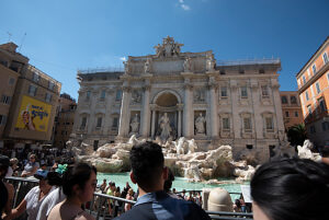 Trevi Fountain with tourists, behind it historic palaces and the Palazzo Poli, Rome, Italy