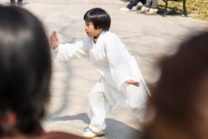 A boy practicing Qigong in the middle of a group of people in Nanjing, China A boy practicing Qigong in the middle of a group of people in Nanjing, China