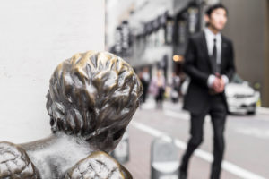 A businessman in a suit beeing watched from a statue