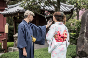 Two people taking selfies in a temple complex in Tokyo
