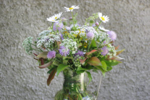 Bouquet of meadow flowers 'impressionistic' in front of a roughly structured wall