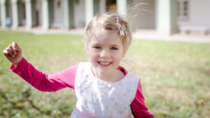 Little girl with blond hair and pink dress, laughing, approaching camera Little girl with blond hair and pink dress, laughing, approaching camera