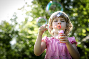 Blonde girl in pink dress blowing soap bubbles Blonde girl in pink dress blowing soap bubbles