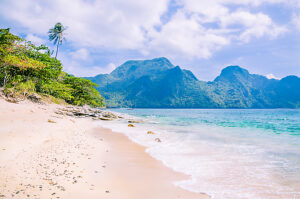 Stunning beach on Helicopter Island in the Bacuit archipelago in El Nido, Cadlao Island in Background, Palawan, Philippines.