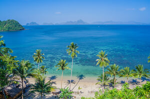 Sandy Beach with Palm Shadows, Huge Rocks in Background, El Nido, Palawan, Philippines.