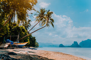 Banca boat on shore under palm trees.Tropical island scenic landscape. El-Nido, Palawan, Philippines, Southeast Asia