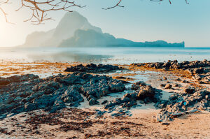 Rocky Beach during low tide in morning light in front of amazing Cadlao Island, El-Nido, Palawan, Philippines.
