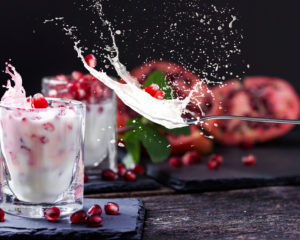 Pomegranate seeds in yogurt and splashing milk on a spoon Pomegranate seeds in yogurt and splashing milk on a spoon