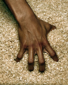 A hand reaches into a barrel of rice. This is an exercise used to build strength in the rehabilitation of hand injury patients.