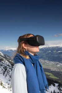 Person mit Virtual-Reality-Brille vor Bergkulisse
