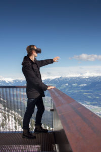 Person mit Virtual-Reality-Brille vor Bergkulisse