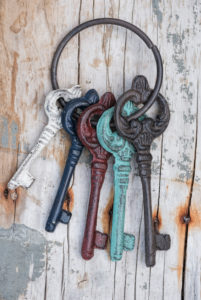 key ring with coloured old keys on old weather-beaten wooden board key ring with coloured old keys on old weather-beaten wooden board