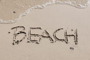 Beach' written in sand, horizontal photograph with small wave washed up on the sand, Beach' written in sand, horizontal photograph with small wave washed up on the sand,