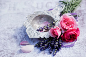 Florale decoration, old silver tea strainer with lavender and pink roses and petals Florale decoration, old silver tea strainer with lavender and pink roses and petals