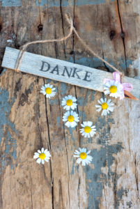 Sign with 'Danke' on old wooden board with small camomile blossoms Sign with 'Danke' on old wooden board with small camomile blossoms