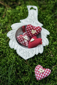 Red hearts in old silver tea strainer in the moss in the forest Red hearts in old silver tea strainer in the moss in the forest