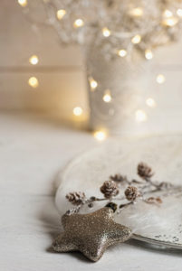 Christmas Still Life with golden glitter star and cones on a white plate, in background Christmas Lights, Christmas Still Life with golden glitter star and cones on a white plate, in background Christmas Lights,