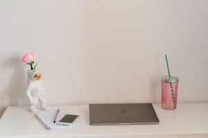 Home office desk with laptop, smartphone, drink and decorative astronaut Home office desk with laptop, smartphone, drink and decorative astronaut