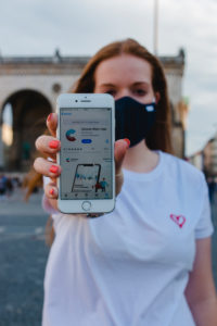 Red-haired woman with Corona warning app on iphone in Munich on Odeonsplatz Red-haired woman with Corona warning app on iphone in Munich on Odeonsplatz