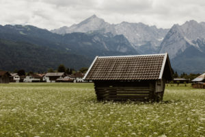 Wooden hut / hay barn in Garmisch-Partenkirchen with alpine panorama in the background Wooden hut / hay barn in Garmisch-Partenkirchen with alpine panorama in the background
