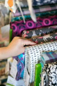 Detail view of fabrics at a sewing workshop, woman selects fabric with an anchor Detail view of fabrics at a sewing workshop, woman selects fabric with an anchor