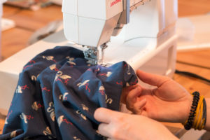 Detail shot of woman sewing on an electric sewing machine with fabric samples Detail shot of woman sewing on an electric sewing machine with fabric samples