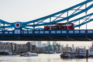 England, London, Double Decker Buses Crossing Tower Bridge with Canary Wharf Skyline in The Back at Dawn England, London, Double Decker Buses Crossing Tower Bridge with Canary Wharf Skyline in The Back at Dawn