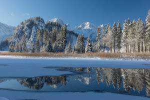 Ameisstein (776 m) mountain at the Lake Almsee in winter. The lake is frozen and snow covered, clear blue sky. Ameisstein (776 m) mountain at the Lake Almsee in winter. The lake is frozen and snow covered, clear blue sky.