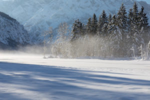 Misty morning on Lake Almsee which is frozen and snow covered. Snow on the forest with blue sky. Misty morning on Lake Almsee which is frozen and snow covered. Snow on the forest with blue sky.