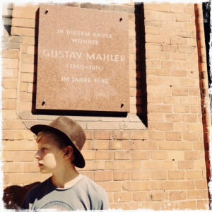 Germany, Hamburg, young boy with hat in front of a memorial plaque