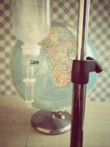 IV pole with infusion bottle in front of a globe with the African continent